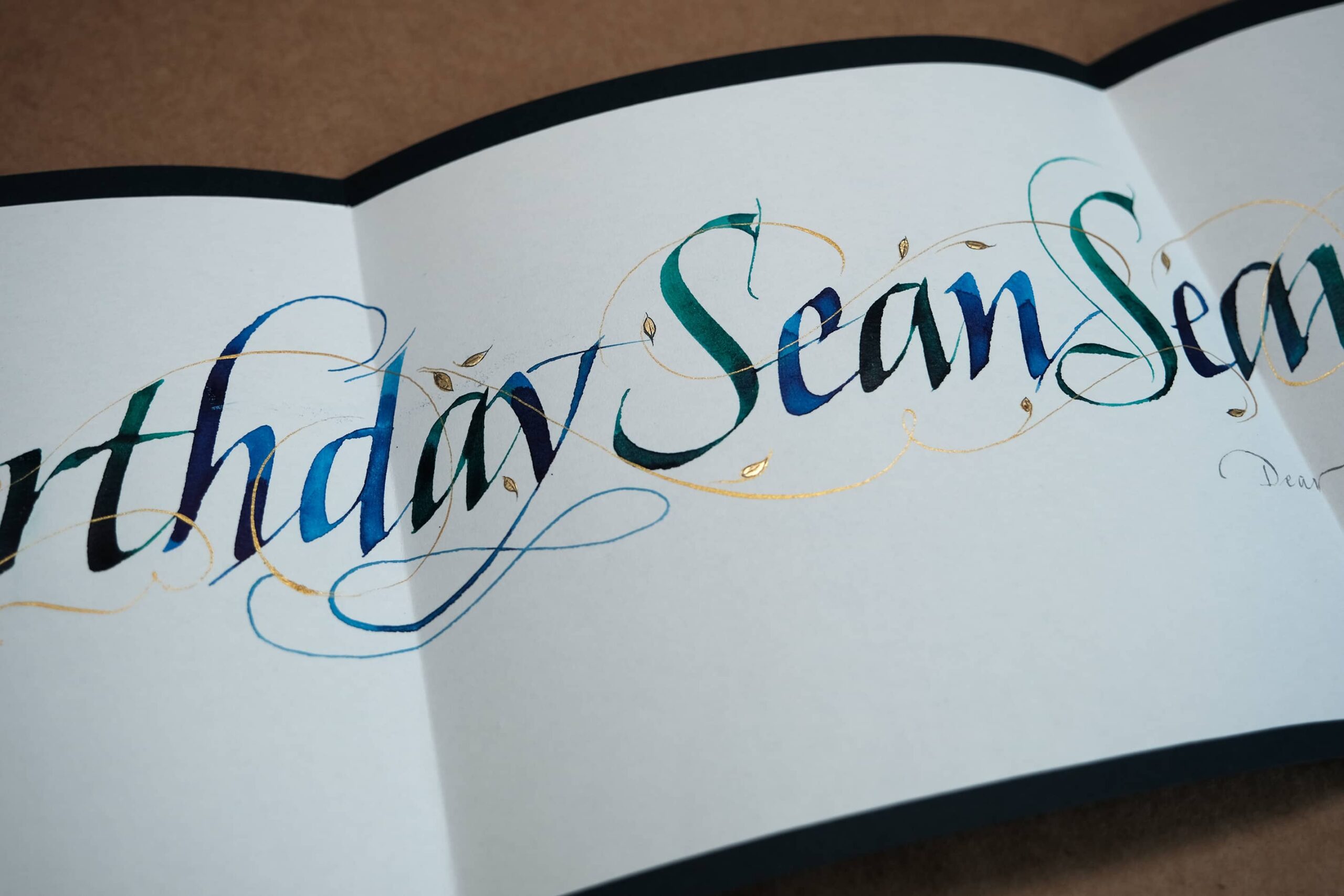 Detail of calligraphy written in water color with gold details.